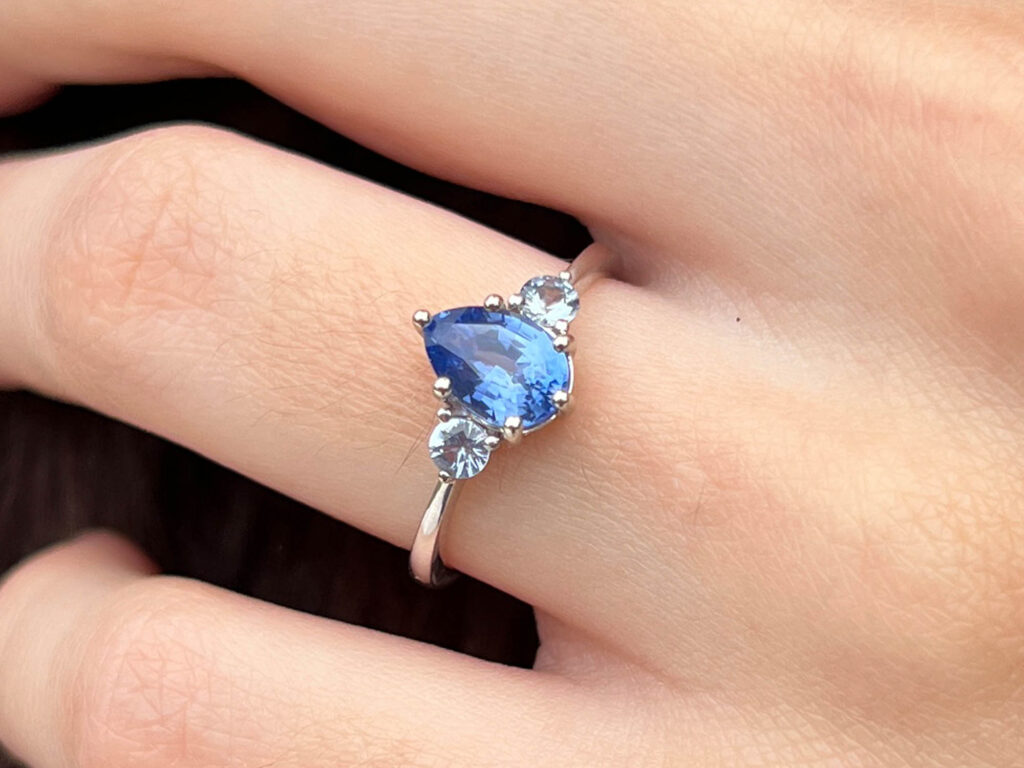 Clarisse Ocean blue sapphire trilogy ring worn on hand for scale